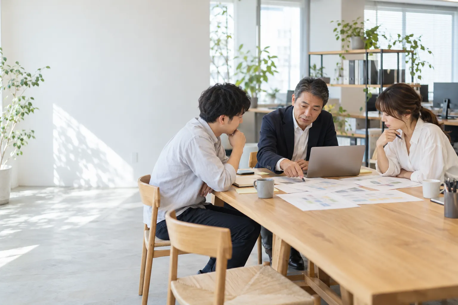 オフィスで業務の流れを確認しながら打ち合わせをする社長と社員